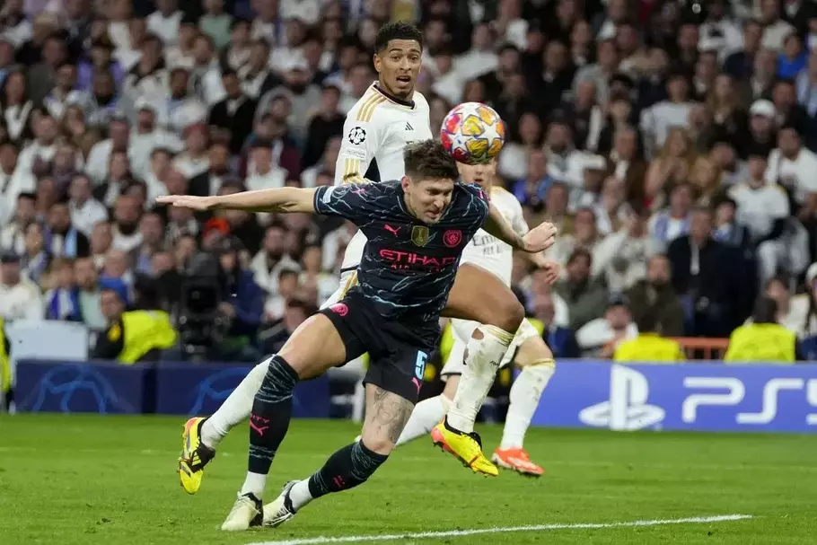 Real Madrid player Jude Bellingham fights for the ball with Manchester City player John Stones (front) in the first leg of the Champions League quarter-final at Santiago Bernabeu Stadium, Madrid, Spain, Tuesday, April 9 2024. - (AP/Manu Fernandez)
